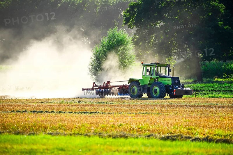 Tractor ploughs a harvested field in a cloud of dust in Kirchwerder, Hamburg, Germany +++ editorial use only