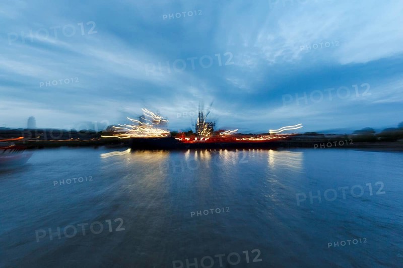 Light trails at dusk, illuminated ship on the river, dynamic motion blur, Elbe, Hamburg, Germany