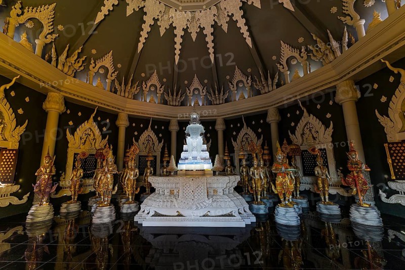 Glass Buddha statue surrounded by figures as heavenly beings and temple guards in the public prayer hall in the Buddhist temple complex Wat Phra That Don Phra Chan, near Lampang, Lampang Province, Thailand