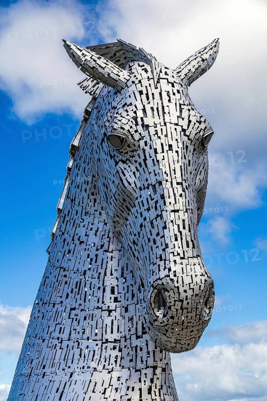 A close-up view of a Kelpie horse-head sculpture against clouds, designed by Andy Scott, one of a pair of monumental, 30-metre-high steel horse-head sculptures. The Kelpies, Helix parkland near Falkirk, Scotland, United Kingdom