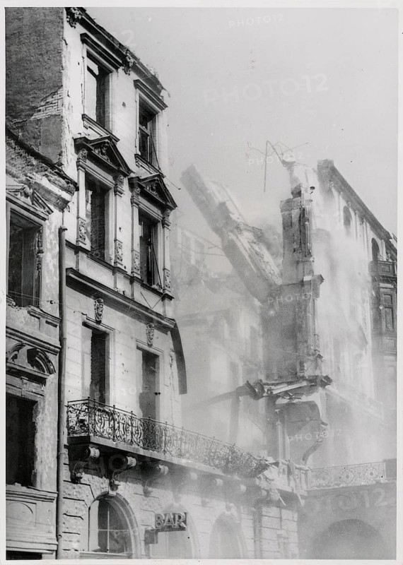 Munich, ruins, bombing, collapsing house wall, World War II, National Socialism, A partially collapsed building with visible ruins and dust clouds in an urban setting, 1944
