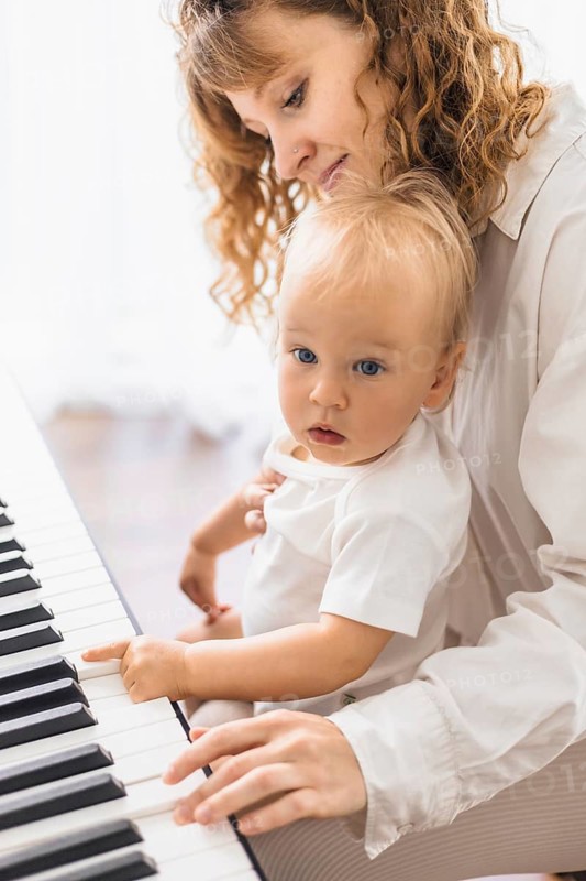 A woman teaches a child at the piano with an intimate, connected interaction
