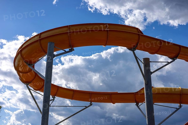 Bright sunlight shines over a fun water slide in a hotel water park in Turkiye. Families and friends gather to enjoy the exciting water attractions during a warm summer day. Active rest in aqua park