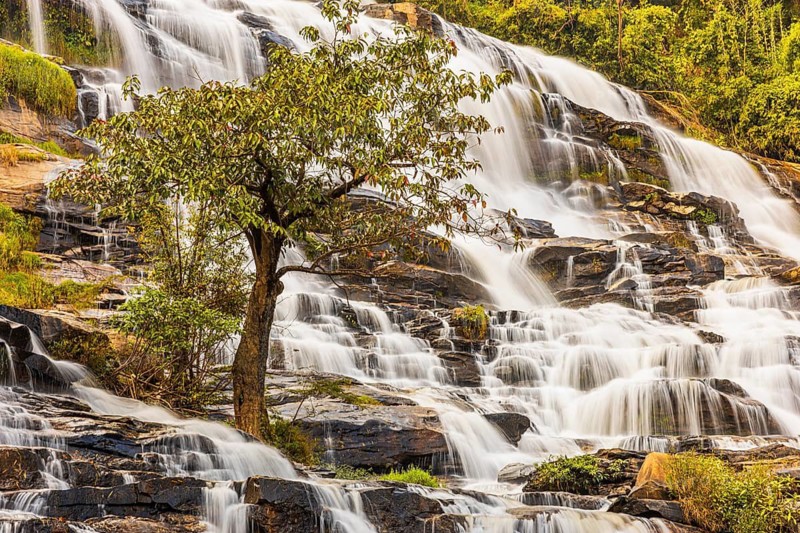Mae Ya waterfall with cascading flowing water surrounded by lush tropical vegetation, near Doi Inthanon National Park, Chiang Mai Province, Thailand