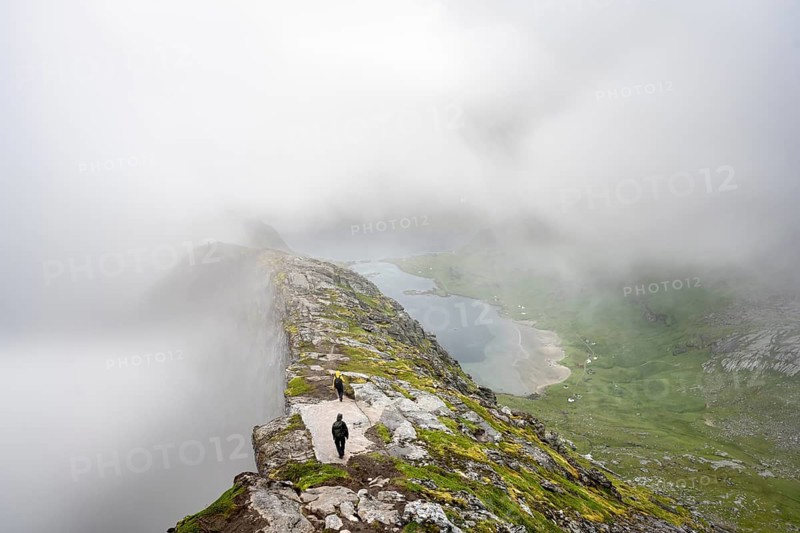 Hikers on the summit of Helvetestinden, cloudy mountain landscape with summit ridge, Lofoten, Norway