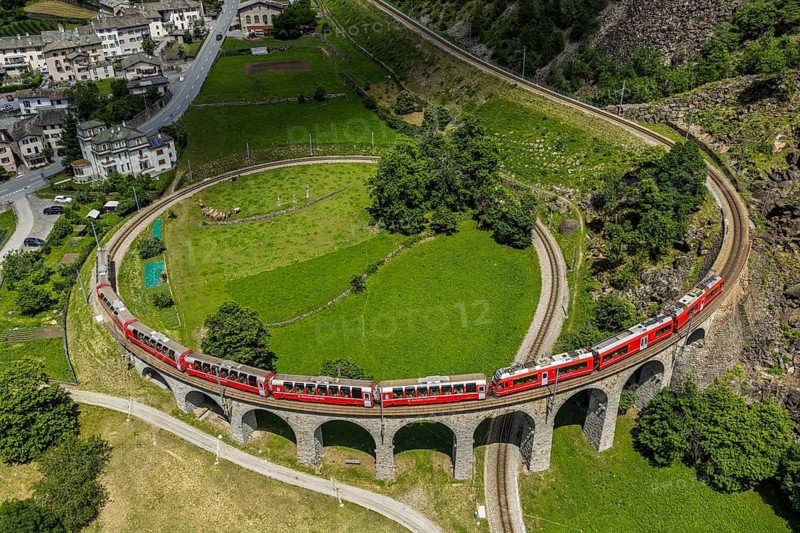Red train of the Rhaetian railroad line, Bernina Express, passing the circular Brusio viaduct, aerial view, Brusio, Switzerland