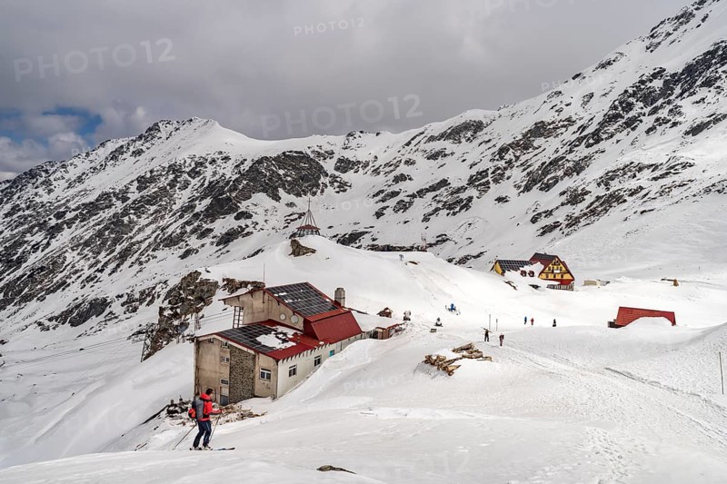 Skiers and mountain huts on snowy Lake Balea in the Fagaras Mountains, South Carpathians, Transylvania, Romania