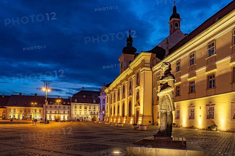 Lazar monument on the Pia?a Mare Great Square and the Catholic parish church of the Holy Trinity at dusk, Sibiu or Sibiu, Transylvania, Romania