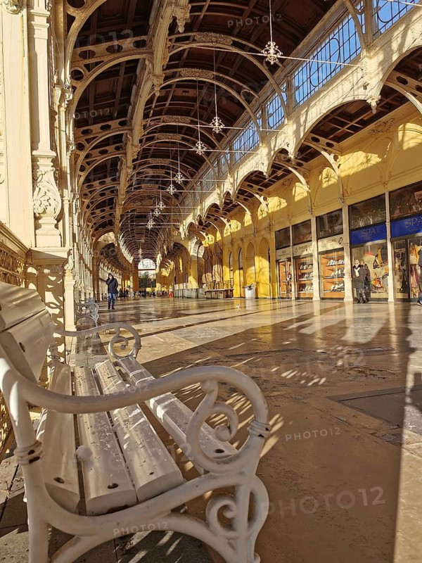 Elegant, sun-drenched corridor with arches and wrought iron bench, Marianske Lazne, Maxim Gorky Kollonade, Marianske Lazne main collonade, Marienbad, Czech Republic