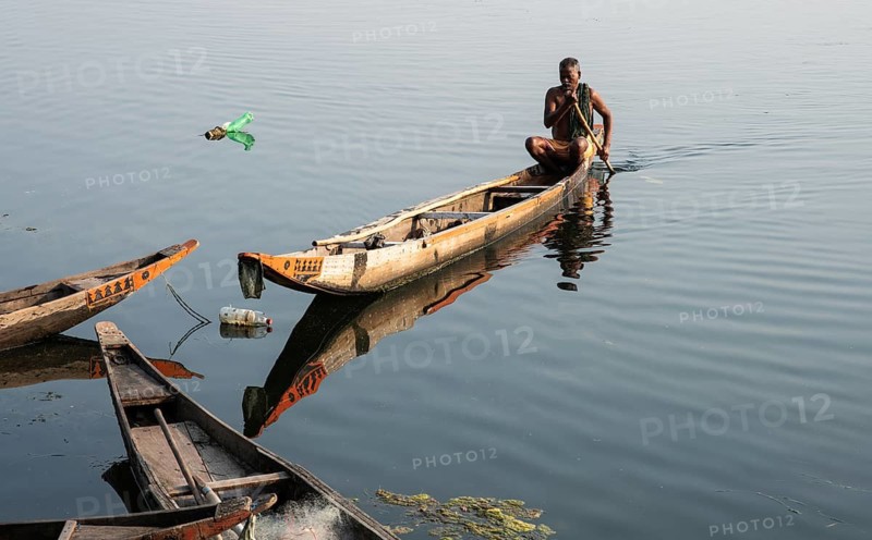Local fisherman, Mahanadi river, Sonepur, Odisha, India. Bottles on the surface of the water are fish traps
