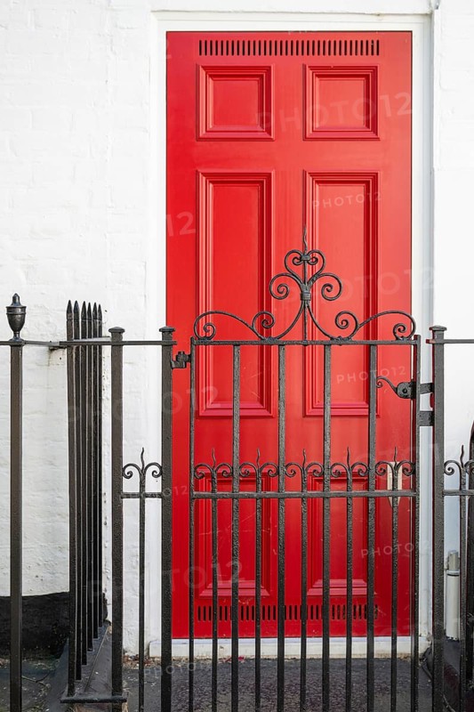 Red door behind stylized black painted metal fence in classic design, Chelsea, London, Great Britain, England, Great Britain