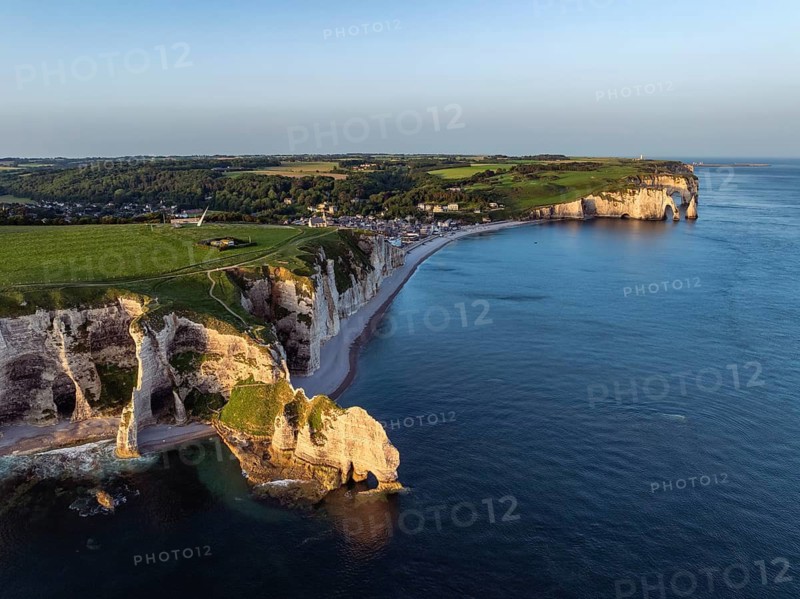 Aerial view of the Porte d'Amont rock formation, Falaise d'Amont shortly after sunrise, a landmark and natural beauty on the chalk coast with the distinctive rock gate, behind it the holiday resort of Étretat with the beach, on the right the Porte d'Aval and La Manneporte rock formations, Alabaster Coast, La Côte d'Albâtre, chalk cliffs, English Channel, Seine-Maritime, Normandy, France