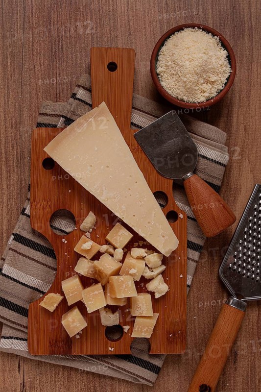 Freshly sliced and grated cheese, parmesan cheese, Gran gusto. Grana padano. on a wooden chopping board, rustic style, no people
