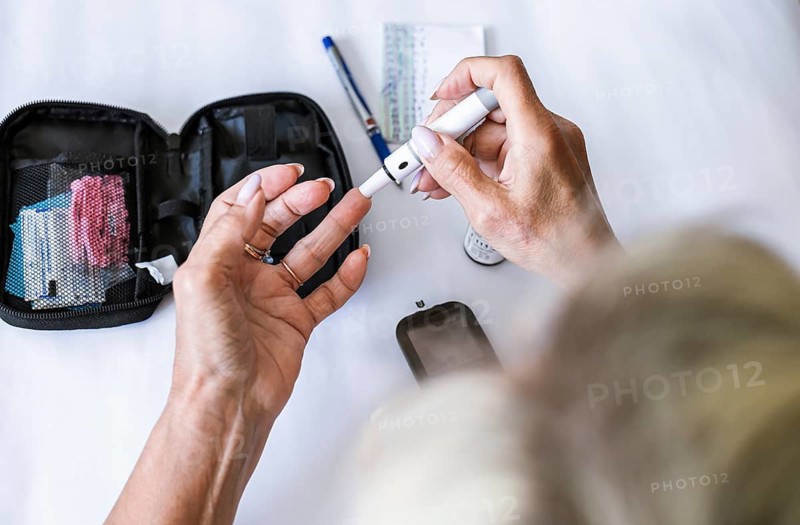 Woman preparing a lancet device for blood glucose testing at home. Diabetes self-care, medical procedure, endocrinology, healthcare routine, prevention and chronic disease management concept