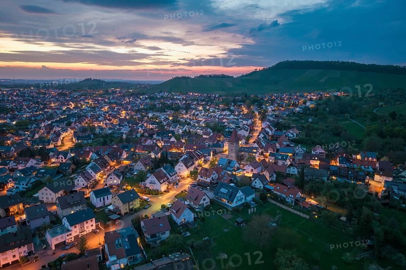 Illuminated urban landscape at dusk with rolling hills and an extensive settlement, Korb im Rems Valley, Baden-Württemberg, Germany