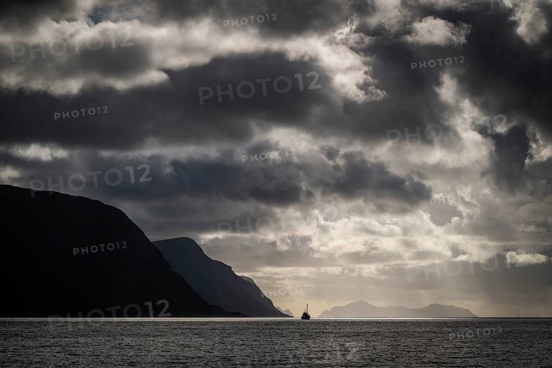 Dramatic lighting and dark clouds over the sea, island, ship, near Ålesund or Alesund, Møre og Romsdal Fylke, Norway