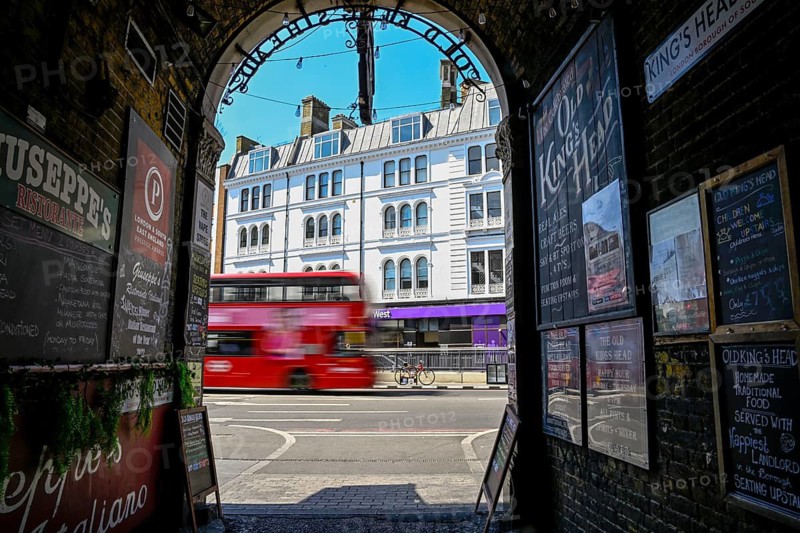 View through the archway of a historic pub onto a passing red double-decker bus, near London Bridge Station, Southwark, London, England, Great Britain, Great Britain