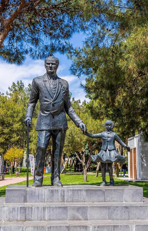 Antalya, Turkiye - April 14, 2025: Statue of Mustafa Kemal Ataturk holding childs hand in public park in Turkey. Monument symbolizing leadership, national identity, and future of younger generations