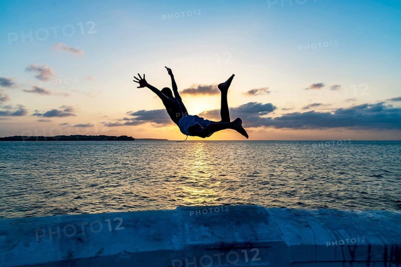 Boy jumping into the sea at sunset in Sao Luis, Maranhao, Sao Luis, Maranhao, Brazil
