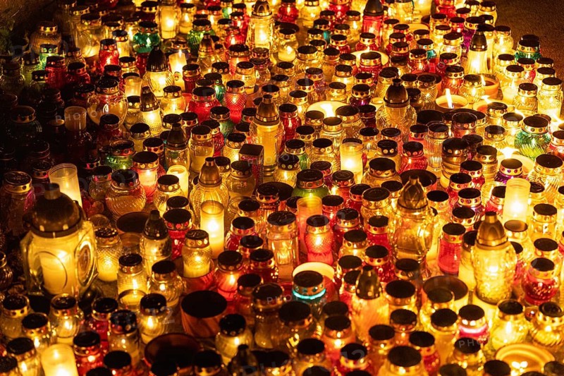 Colorful candle jars glowing warmly at cemetery on all saints day. A huge number of multicolored burning candles and lamps at a cemetery during All Saints' Day celebrations. Warsaw, Poland