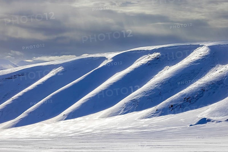 Snow covered mountain slope in Arctic landscape at Mohnbukta, bay at the western shore of Storfjorden in Sabine Land at Spitsbergen, Svalbard