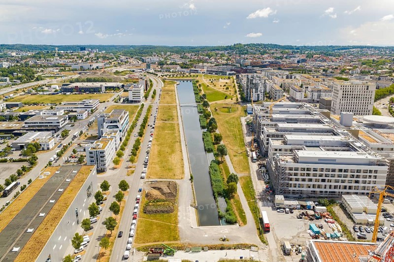 Modern urban landscape with a narrow canal and surrounding green spaces under blue skies, new hospital building, Böblingen airfield, Germany