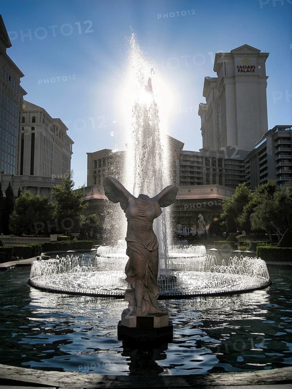 Replica of the famous goddess of victory, Nike of Samothrace, sculpture, back light, sun rays, fountain, water fountain in front of the Caesars Palace Hotel and Casino, Las Vegas Boulevard, Las Vegas Strip, Las Vegas, Nevada, USA