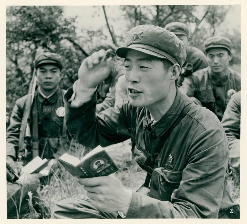 China, People's Republic, Mao Tze-dong, Cultural Revolution, Red Guards, Mao Bible, Communism, Soldier in Uniform reading from a small book about other soldiers in nature, around 1965