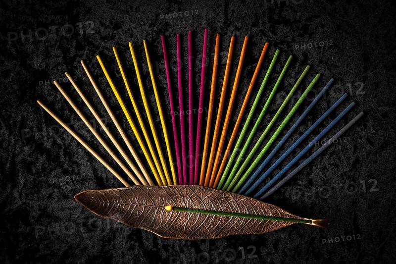 Colorful incense sticks and an incense holder arranged on a black background