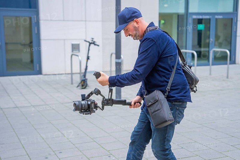 Man with camera and gimbal records outside an office building, Milaneo, Stuttgart, Germany