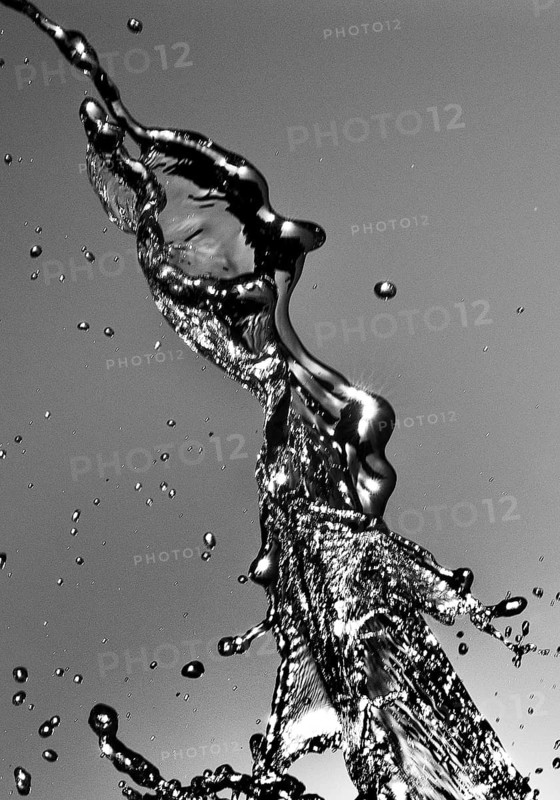 Water frozen by short exposure moving in backlight in front of the sun