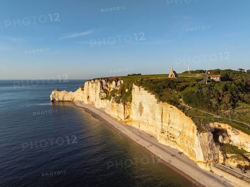 Aerial view of the Porte d'Amont rock formation and landmark, Falaise d'Amont in the evening sun with the Notre Dame de la Garde chapel, Étretat, Alabaster Coast, La Côte d'Albâtre, chalk cliffs, English Channel, Seine-Maritime, Normandy, France