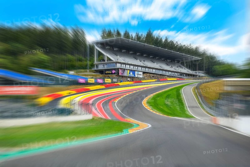 Photo with speed effect from perspective view of racing car racing car drivers for motorsport from leading position on front high speed curve left turn with below flowing stream Eau Rouge from circuit de Spa Francorchamps Spa-Francorchamps racetrack, behind steeply rising right turn Raidillon and large stand, Stavelot, Ardennes, Walloon region Wallonia Wallonia, Belgium
