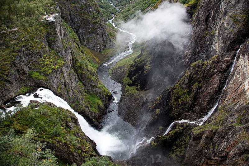 Majestic waterfall flowing through a narrow and lush gorge, Voringsfossen, with 165m drop, above the village of Eidfjord, Hardangerfjord, Norway, Scandinavia