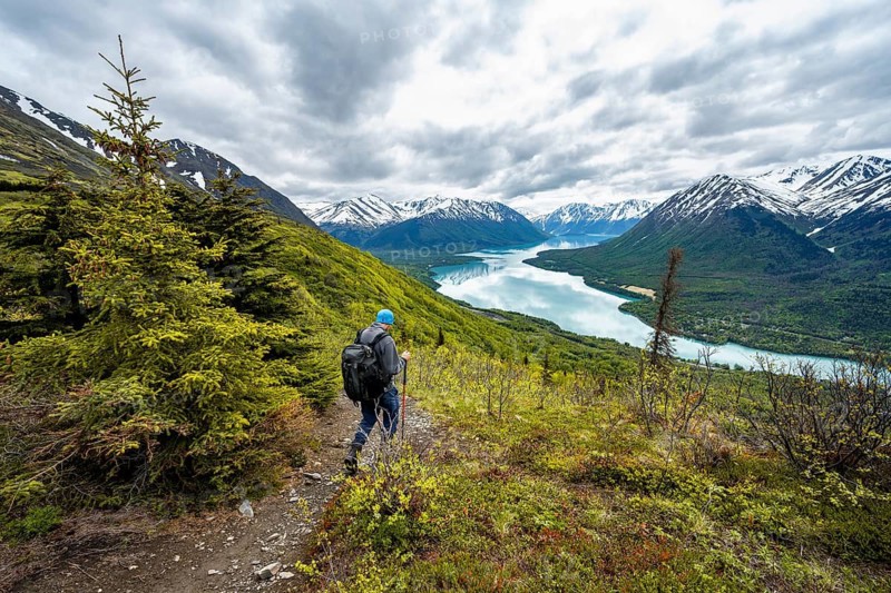 Climbers on a hiking trail, Slaughter Ridge Trail, view of snowy mountains in spring and turquoise blue Kenai Lake Lake, Cooper Landing, Kenai Peninsula, Alaska, USA