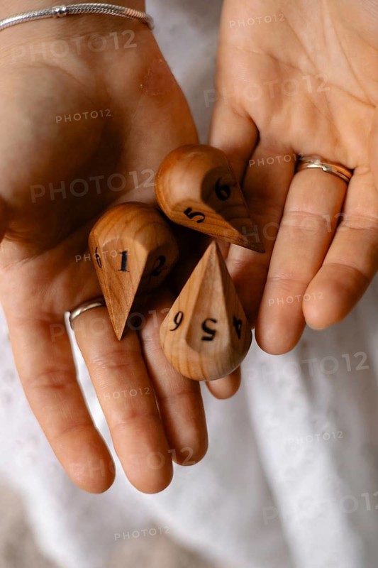 Close-up of hands holding numbered wooden dice, showcasing their detailed texture