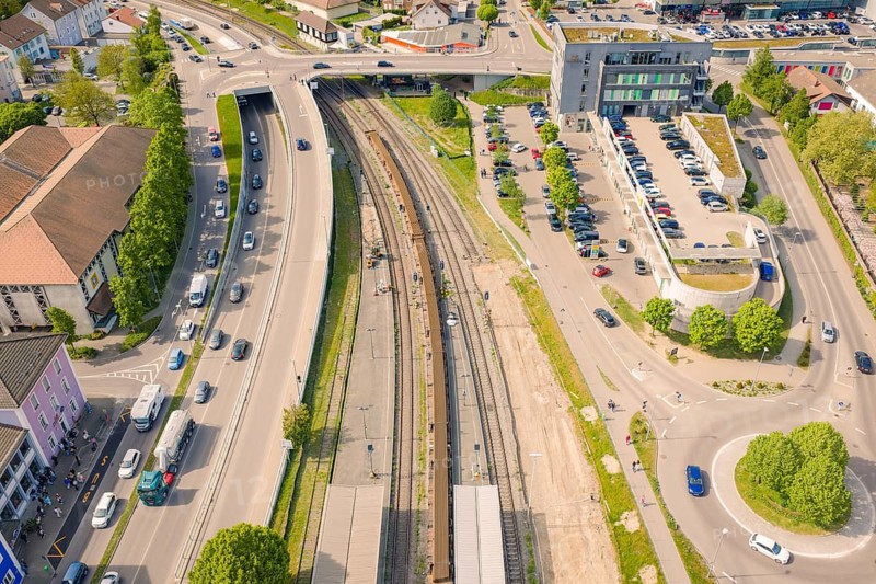 Station environment with rails, surrounded by roads and cars, airy urban setting, construction site by Leonhard Weiß to renovate the train station and build the overhead line, Waldshut, Germany