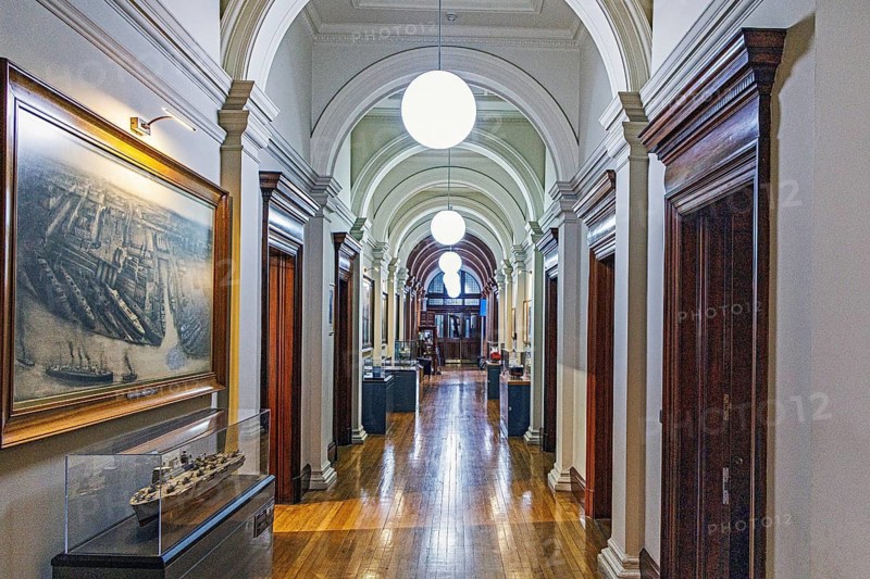 Vaulted corridor lined with arches, a ship painting and model display cases at the former Fairfield shipyard offices, Govan, Glasgow, Scotland, United Kingdom
