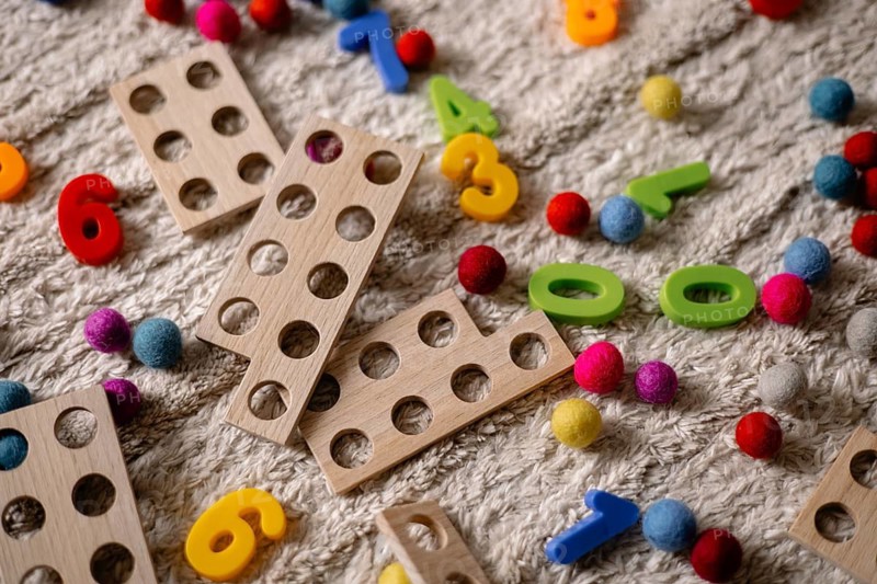 Wooden counting toys and scattered colorful balls on a textured surface