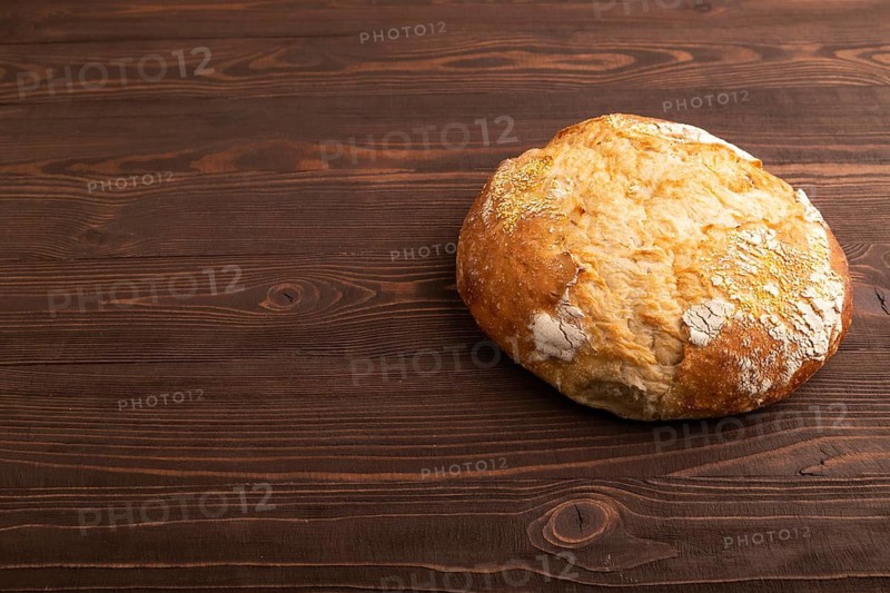 Homemade bread on brown wooden background, copy space, side view