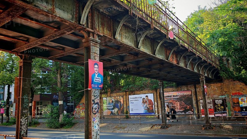 Görlitz railway bridge, rusty old bridge with posters and graffiti in an urban environment, surrounded by trees, Alt Treptow, Berlin