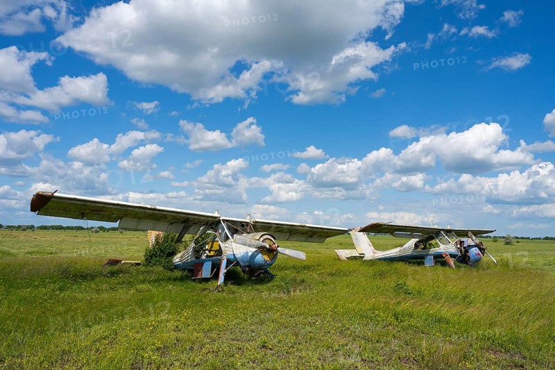 Two abandoned aircraft stand in a green field against a cloudy sky, PZL-104 Wilga multi-purpose aircraft, abandoned airport, Ceadir-Lunga, Ceadîr-Lunga, Chadyr-Lunga, Taraclia district, Gagauzia autonomous region, Republic of Moldova, Moldova