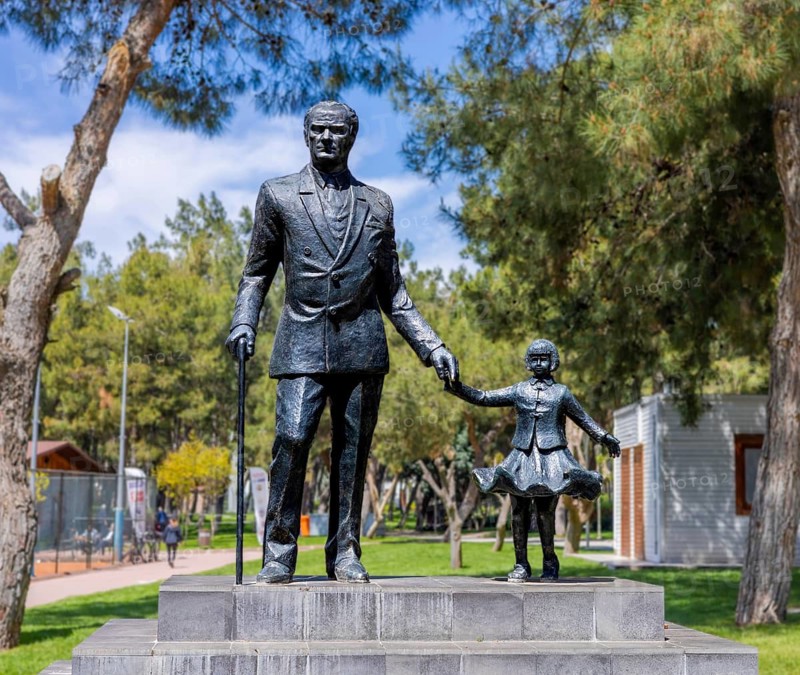Antalya, Turkiye - April 14, 2025: Statue of Mustafa Kemal Ataturk holding childs hand in public park in Turkey. Monument symbolizing leadership, national identity, and future of younger generations