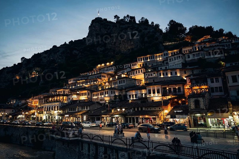 BERAT, ALBANIA - JULY 2, 2026: Illuminated traditional Ottoman houses of Mangalem quarter glowing on the hillside at night beneath the fortress rock