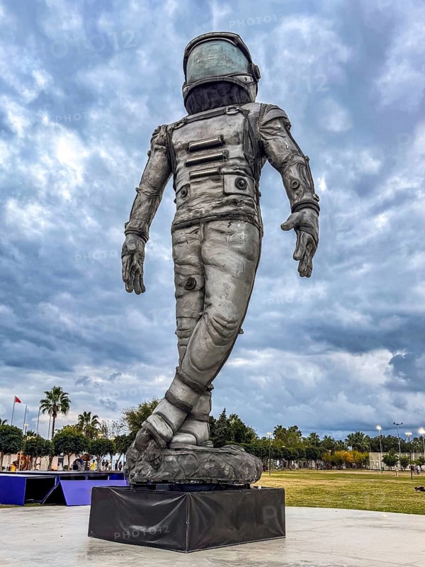 Antalya, Turkiye - 25.10.2025: A large astronaut statue stands in a park under a cloudy sky. The sculpture is detailed and depicts a space suit with a helmet