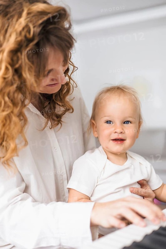 Mother and child interact warmly with piano keys, showcasing mutual affection