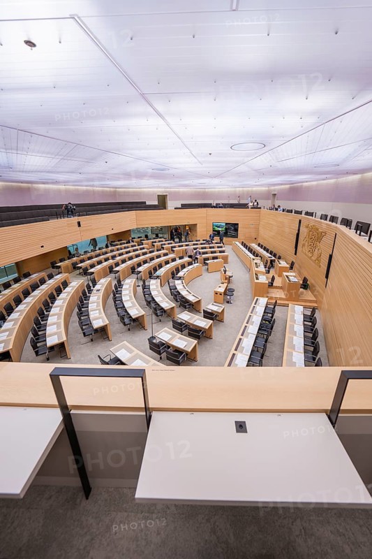 Large meeting room with curved rows of wood under a bright ceiling, Baden-Württemberg State Parliament, Stuttgart, Germany