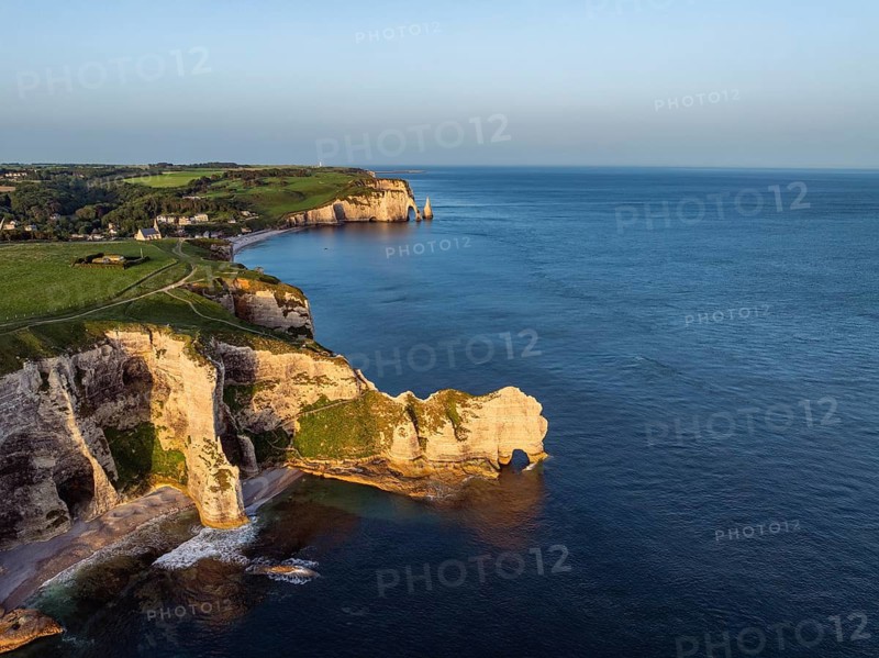 Aerial view of the Porte d'Amont rock formation, Falaise d'Amont shortly after sunrise, a landmark and natural beauty on the chalk coast with the distinctive rock gate, behind it the holiday resort of Étretat with the beach, on the right the Porte d'Aval rock formations, Alabaster Coast, La Côte d'Albâtre, chalk cliffs, English Channel, Seine-Maritime, Normandy, France