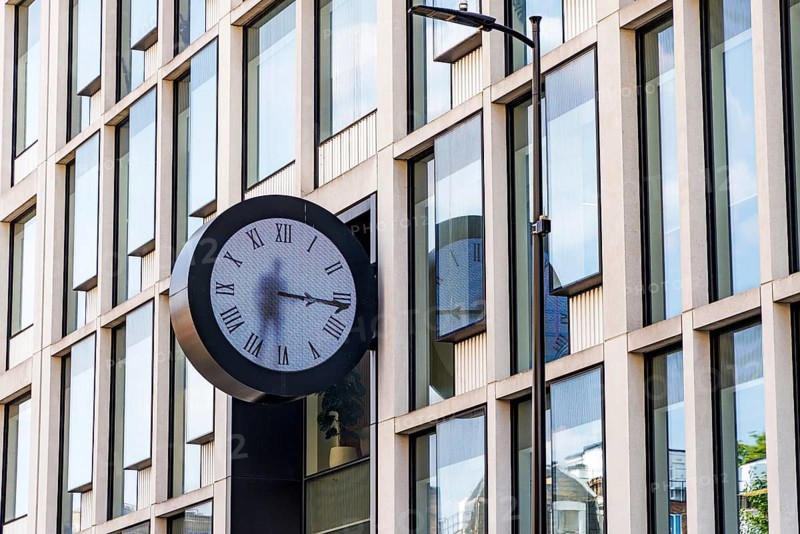 The real-time clock at Paddington containing an image of a man painting and erasing the hands of time created by Maarten Baas is mounted on the glazed facade of a modern office building at Paddington, London, England, United Kingdom