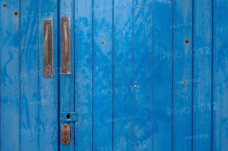 An old wooden door in strong blue with metal handles and visible patina, Majorca, Balearic Islands, Spain